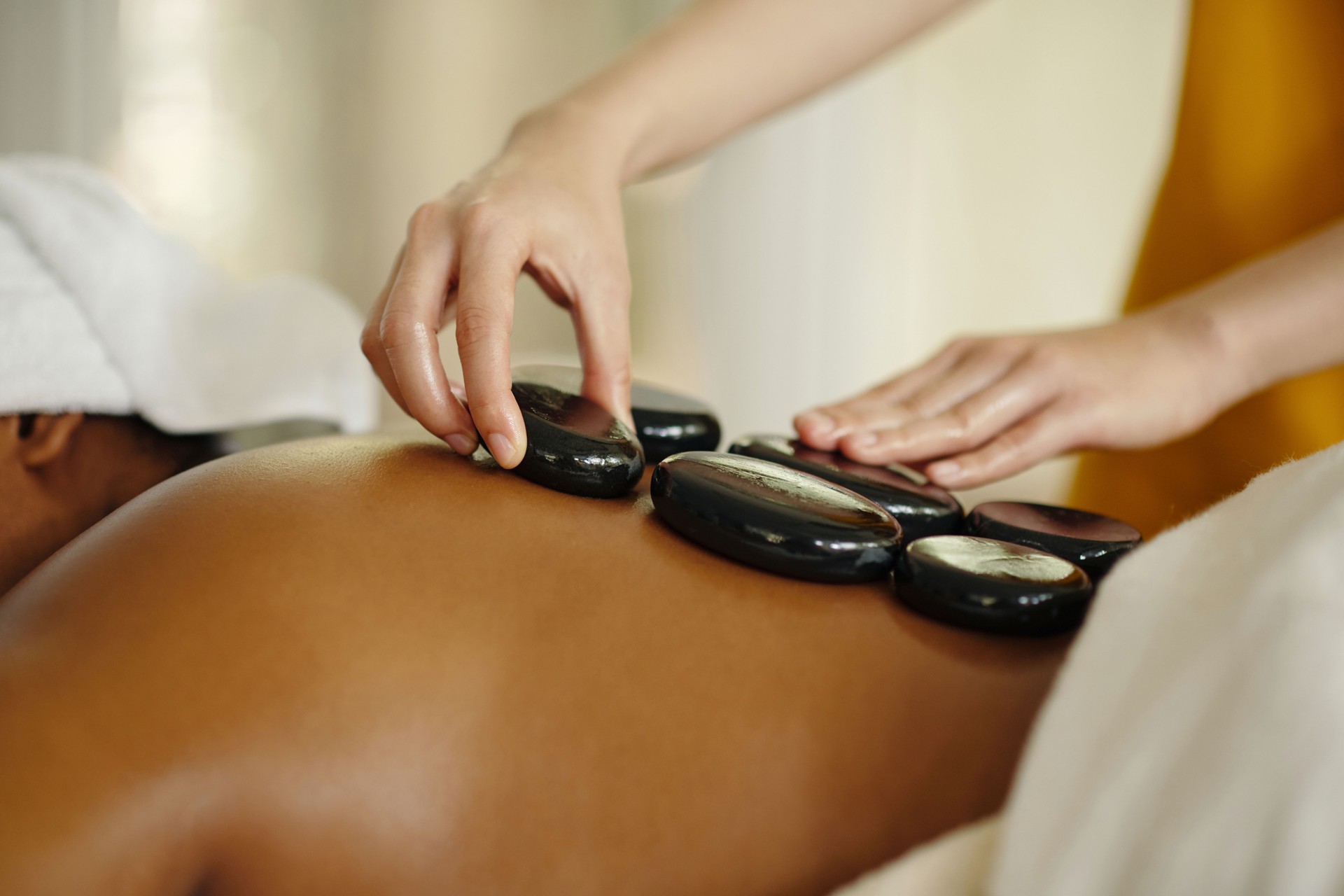 Therapist performing hot stone massage on client’s back for muscle relief